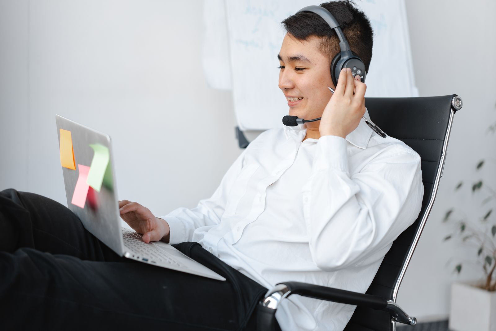 Man in a long-sleeved top working at a laptop with a headset at a desk