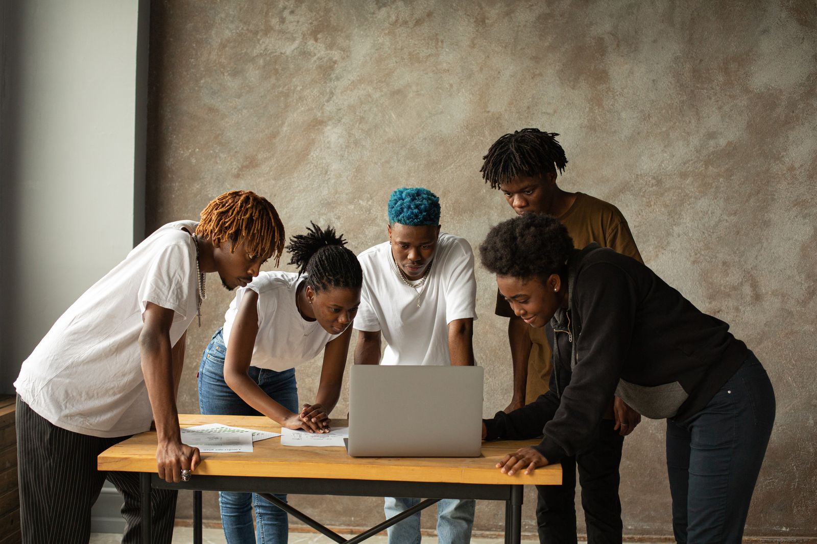 Office colleagues in everyday clothes talking together around a laptop