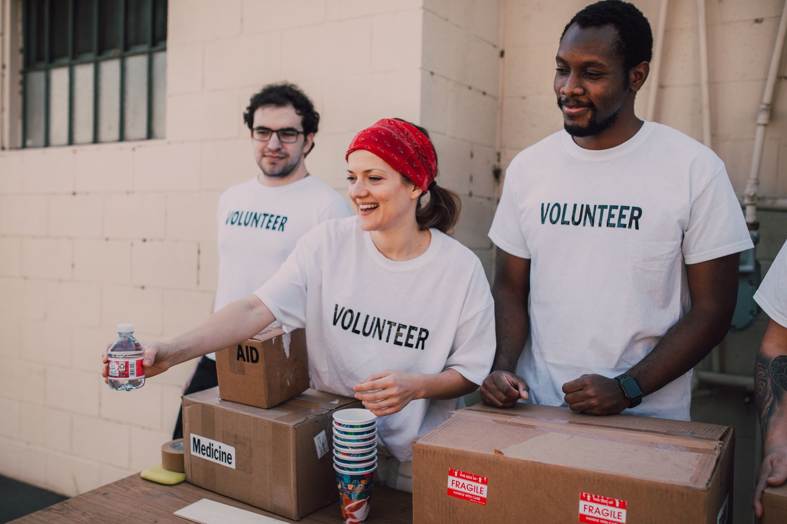 Volunteers in everyday t-shirts packing aid boxes on an outdoor table