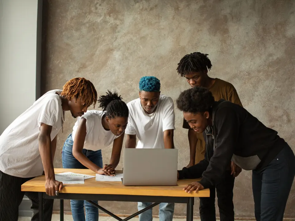 Office colleagues in everyday clothes talking together around a laptop