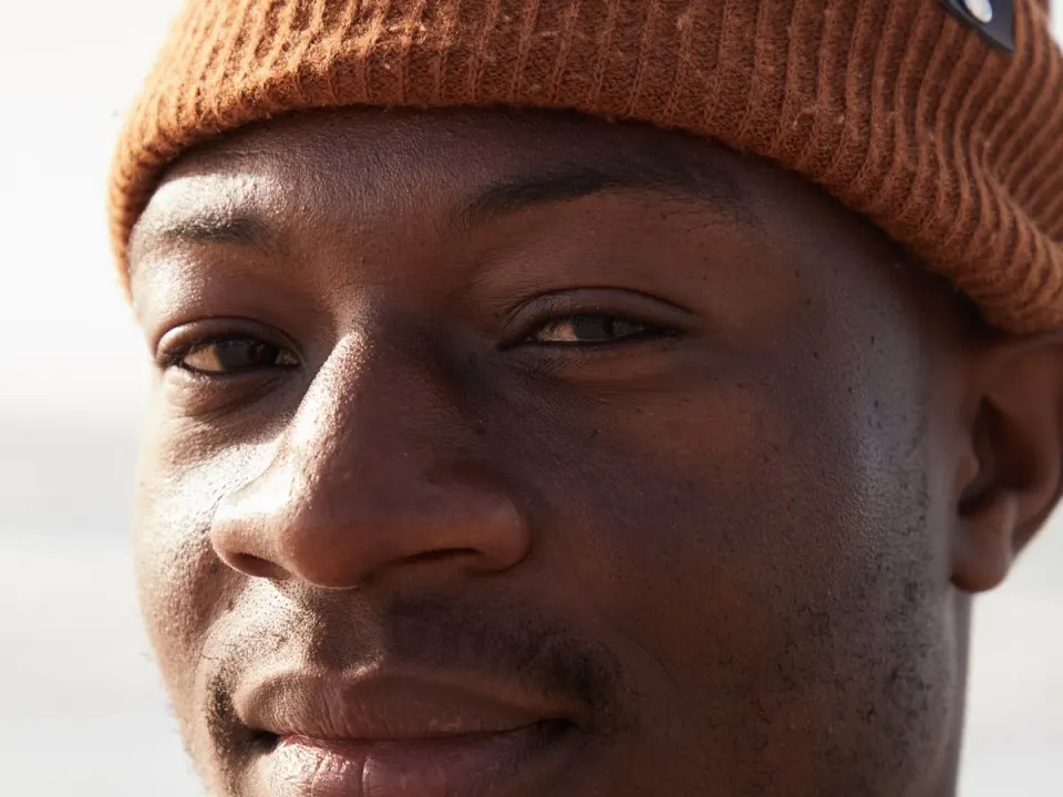 A man in a brown beanie standing outdoors in natural daylight