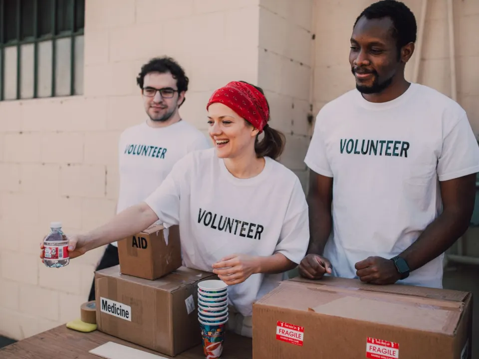 Volunteers in everyday t-shirts packing aid boxes on an outdoor table