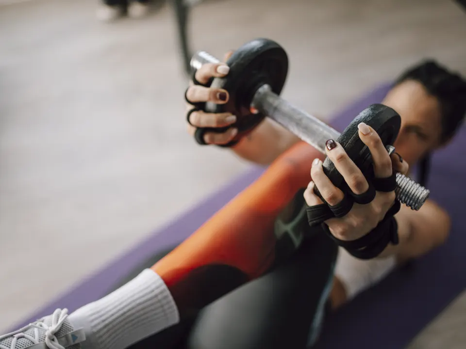 Close-up of gloved hands holding a dumbbell during a floor strength exercise