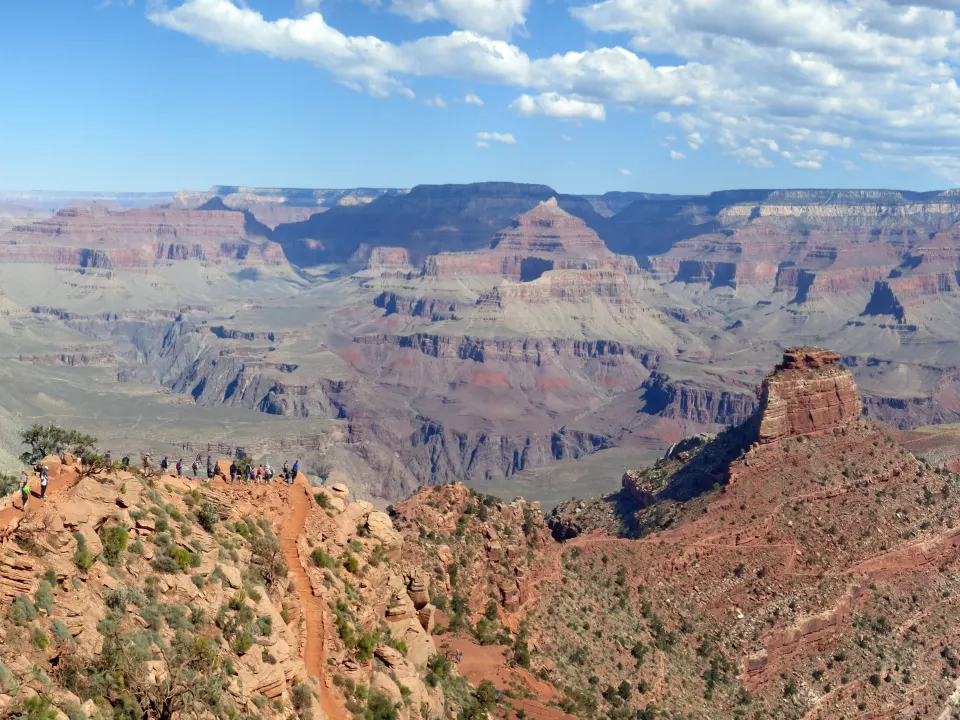 A group in long sleeves hikes along a desert trail