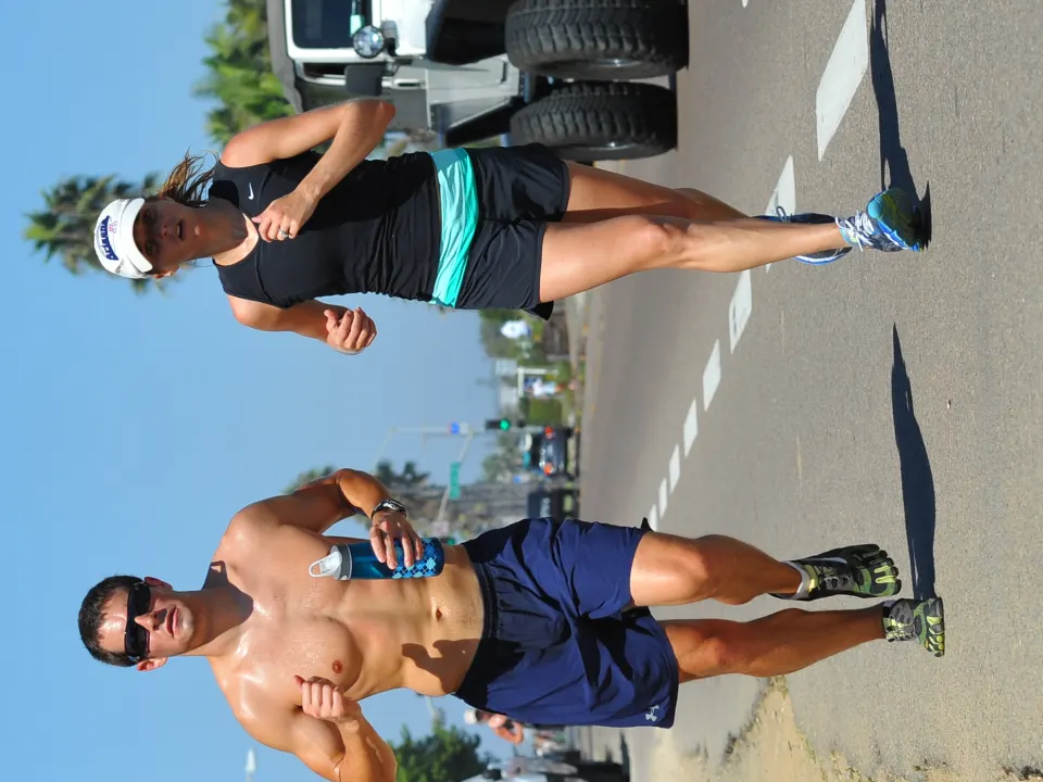 Two people run along a roadside path in modest running clothes