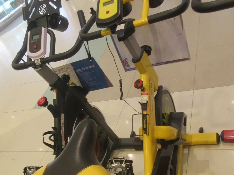 A person in athletic clothing rides an indoor exercise bike in a gym