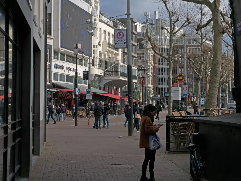 People walking and standing on a brick city square surrounded by buildings