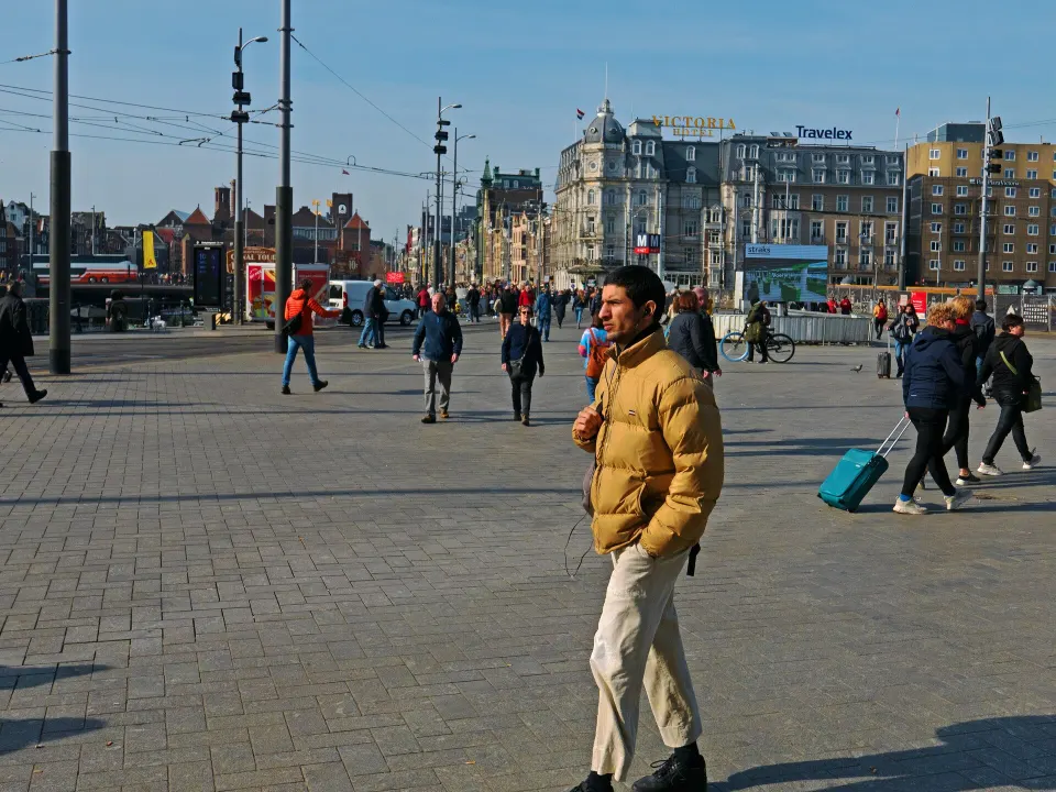 A man walking with other people across a city station square