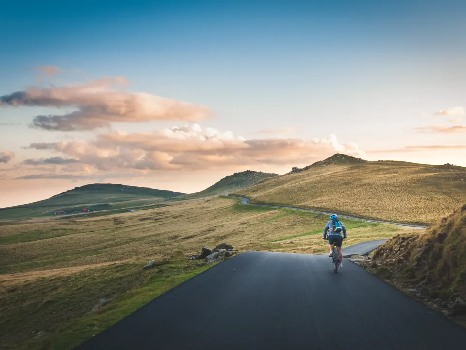 A cyclist riding through green countryside hills